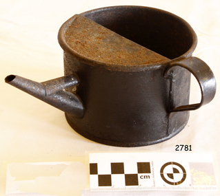 A slightly rusty metal ink kettle or jug with a spout, and a handle on the side.