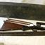 Wooden case with disassembled shotgun parts on a bench