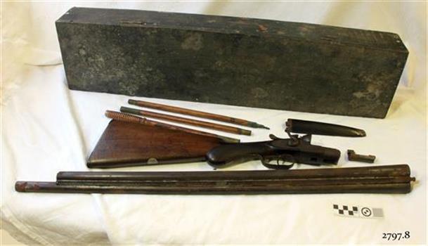 Wooden case with disassembled shotgun parts on a bench
