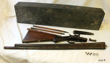 Wooden case with disassembled shotgun parts on a bench