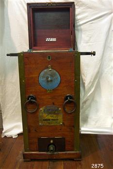 Mahogany box shaped case with dial on front and machinery within.