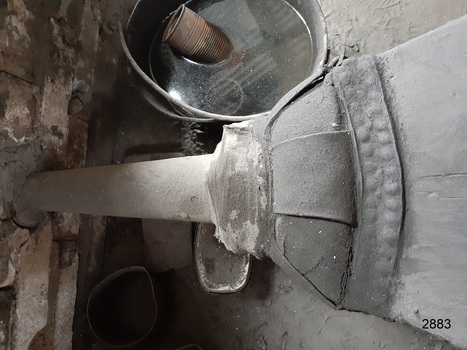The nozzle of the bellows is blowing into the forge, showing the joint of the nozzle and bellows.