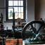 Green panted machine with red painted piston, and wheel attached to a drive blet. 