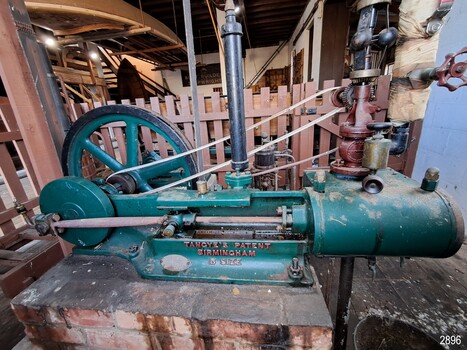 Green painted horizontal metal machine with fly wheel and belt, and governor