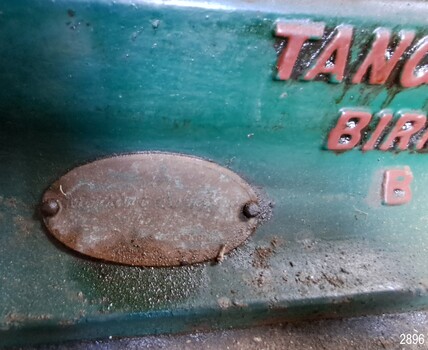 Oval metal plate attached to the engine front with details of the distributor