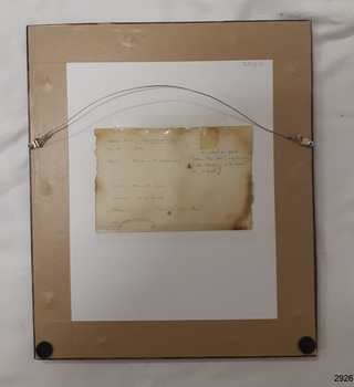 Brown paper backing sheet with attached label showing an inscription