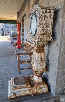 Upright scale has fancy decoration on the side, and small wheels under the platform