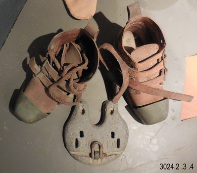 boots have a thick sole, metal toe caps, leather body and three leather straps that buckle around the ankles.