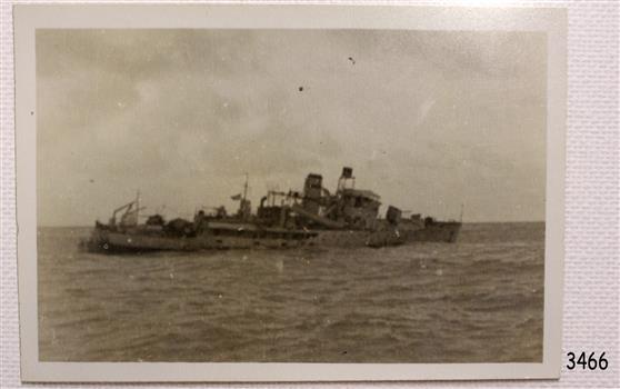 Black and white photo shows sinking ship with damage to above board structure