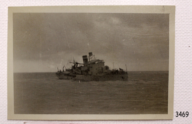 Ship is leaning as it sinks into the sea. Structures on deck are damaged.
