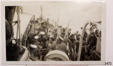 Survivors being transferred from one vessel to another with the help of other seamen.