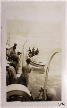 Central subject is a small vessel beside a ship. Figures on the vessel are facing figures on the ship.