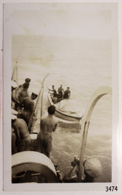 Central subject is a small vessel beside a ship. Figures on the vessel are facing figures on the ship.