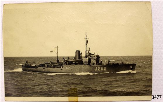 Black and white image of a ship on open sea travelling towards the right side of the image