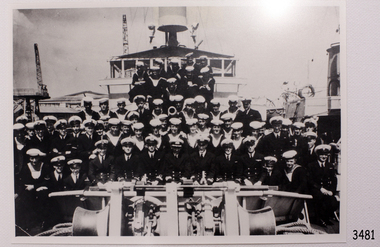 Crew in uniform arranged in rows on the bow of the ship., which is docked