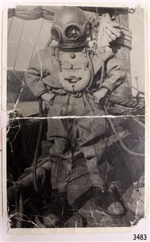 Black and white photograph of a diver on board a sailing vessel at sea