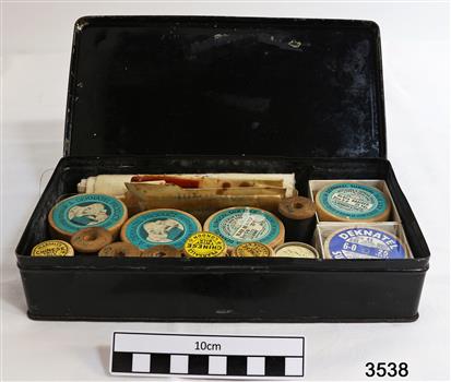 A black tin box containg a variety of surgical silks, sutures and scalpels.