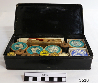 A black tin box containg a variety of surgical silks, sutures and scalpels.