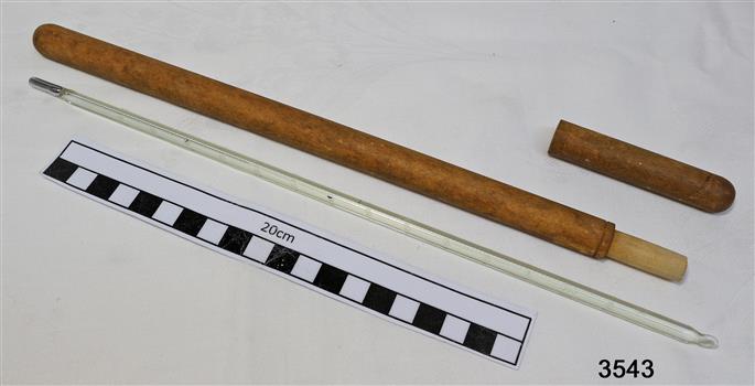 A long glass thermometer with mercury bulb, inside a lightweight wooden cylinder with top