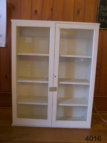 Glass fronted white wood lockable cabinet with four shelves.