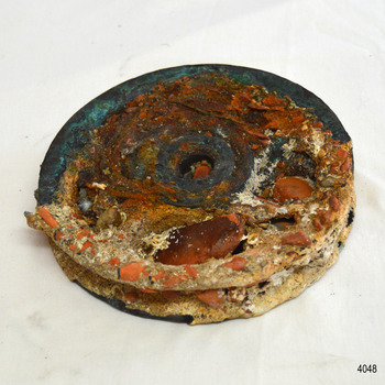 This side is also encrusted but reveals more metal.