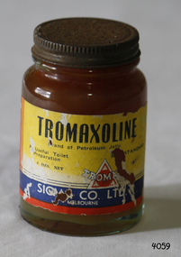 A small brown coloured bottle, with a yellow, red and blue label with the brand name in a white font, with a metal lid.