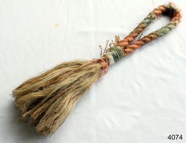 A brush made from a piece of orange and green rope that has been unravelled at the end and tied to form the actual  brush bristles.