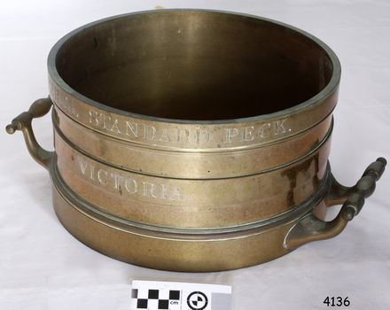 Brass cylindrical vessel with two handles and engraved text
