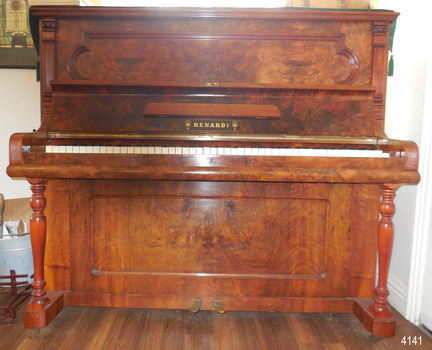 The underside of the lid is also polished wood. There is a narrow, folding music ledge in the centre of the lid. Below the lidge is the maker's name in gold letters.