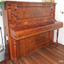 Upright piano, polished wood, etched panels, turned legs, decorative carving on front panel and sides of keyboard 