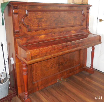 Upright piano, polished wood, etched panels, turned legs, decorative carving on front panel and sides of keyboard 