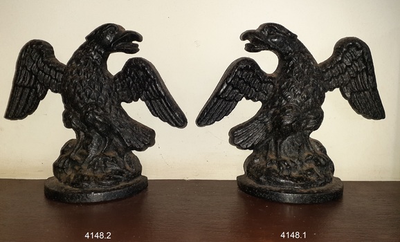 Iron bookends, cast and hollow, facing each other. Details include fairhers.