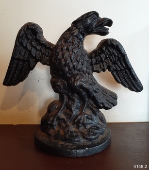 Eagle's beak is open, head and tail viewer's right, claws open and on the ground