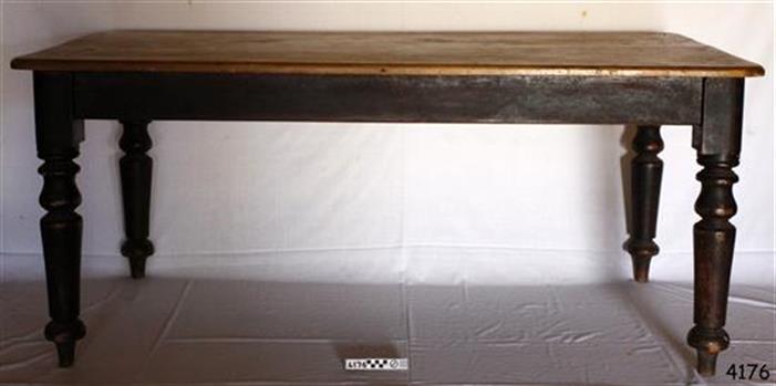Rectangular table has light coloured top and dark stained, turned legs