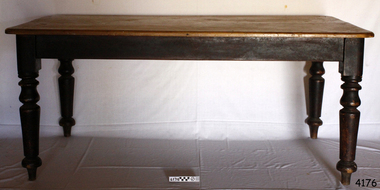 Rectangular table has light coloured top and dark stained, turned legs