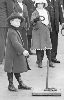 Period photograph showing two children in winter clothing playing quoits. 