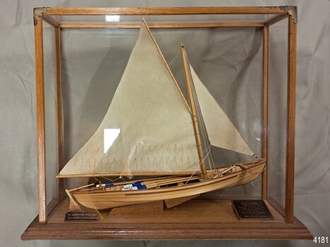 Wooden ship with two sails, mounted in a glass case with wooden frame, Two plaques included.