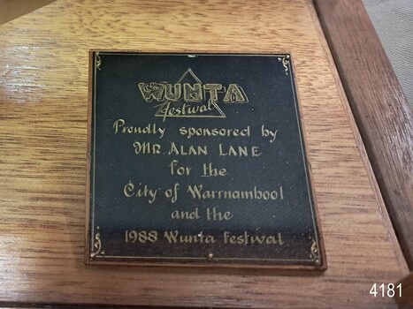 Square black plaque with gold embossed border and sponsor's details