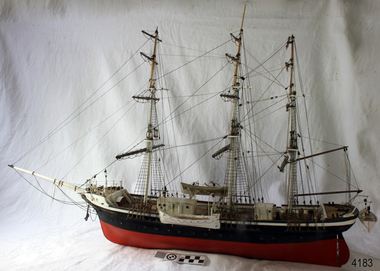 Model sailing ship with black and red hull and three masts