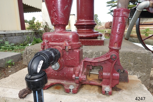 Modern plumbing fittings are attached to the early-to-mid 20th century pump, allowing it to be used as part of the display