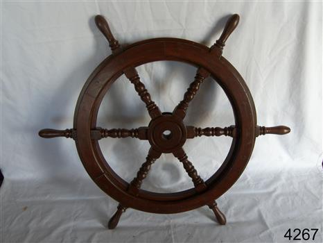 Upright wooden ship's wheel with six turned, decorative spokes