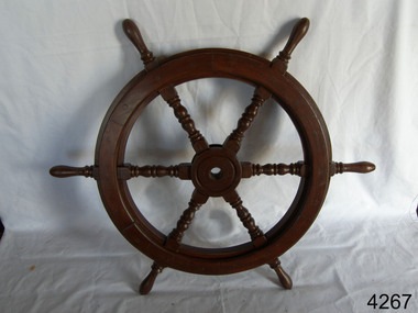 Upright wooden ship's wheel with six turned, decorative spokes