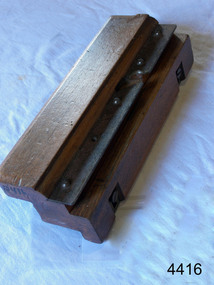 Rectangular varnished wooden tool with attached metal plates and inscriptions