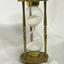 Metal frame with etchings, and a glass hourglass within the frame