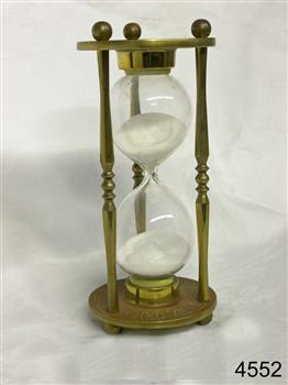 Metal frame with etchings, and a glass hourglass within the frame