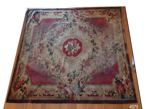 Tablecloth flat on floor, front upwards. Burgundy border with floral pattern.