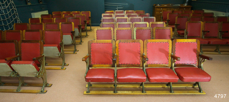 Sixteen banks of red leather covered chairs on wood and metal frames