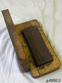 Rectangular wooden base and lid. Base has semi-recessed oil stone