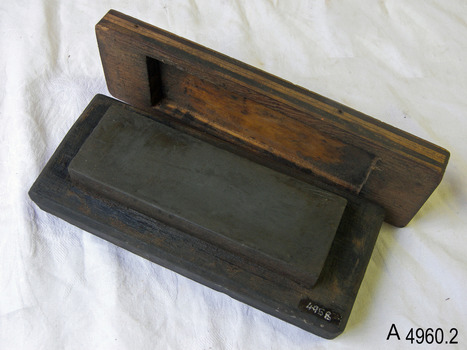 Rectangular block of stone within a recessed wooden block, with a matching wooden lid.