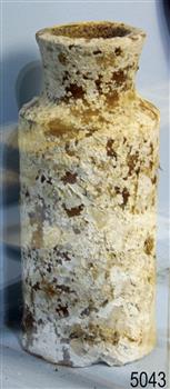 White clay bottle with wide mouth. Encrustations are on the surface.